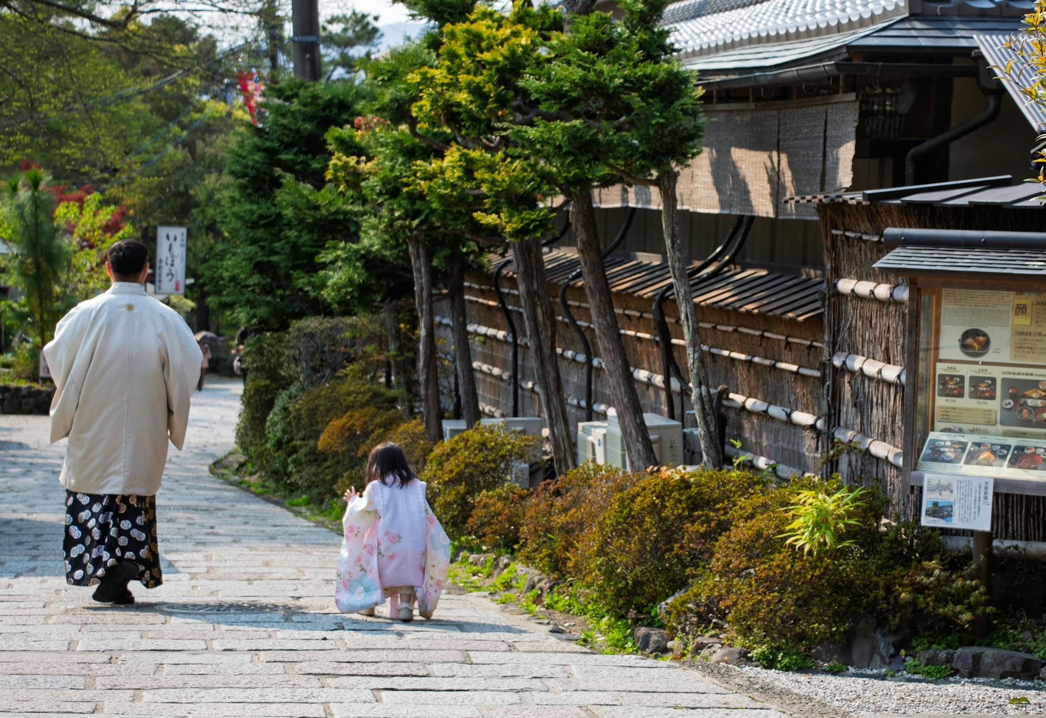 A parent and child in traditional attire walking in a picturesque Kyoto street.